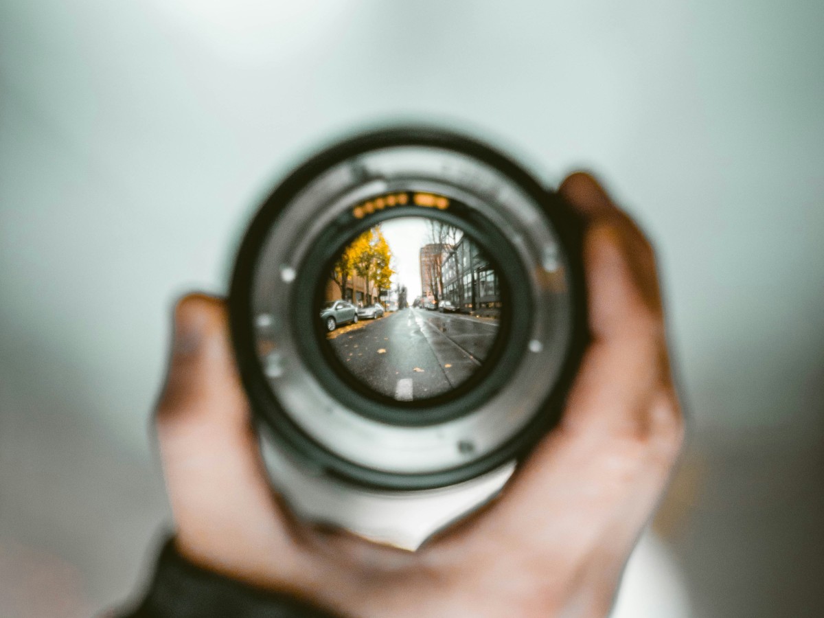 Lens held up by a person with a road coming into focus